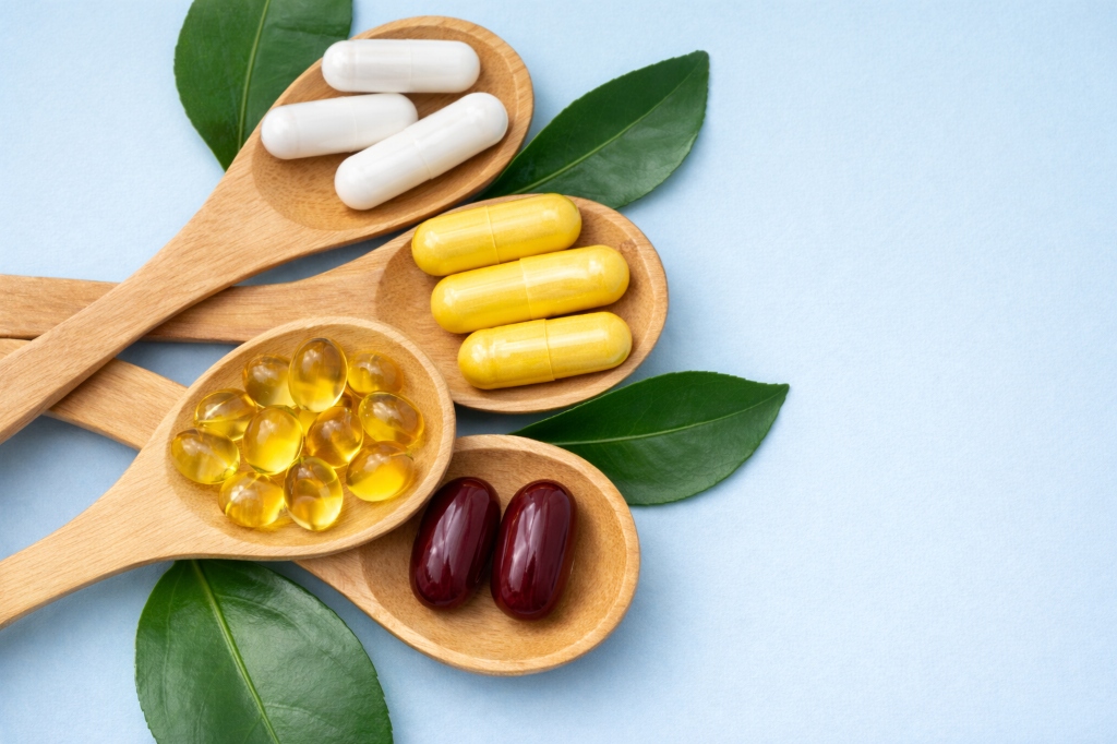 Various supplement capsules on wooden spoons